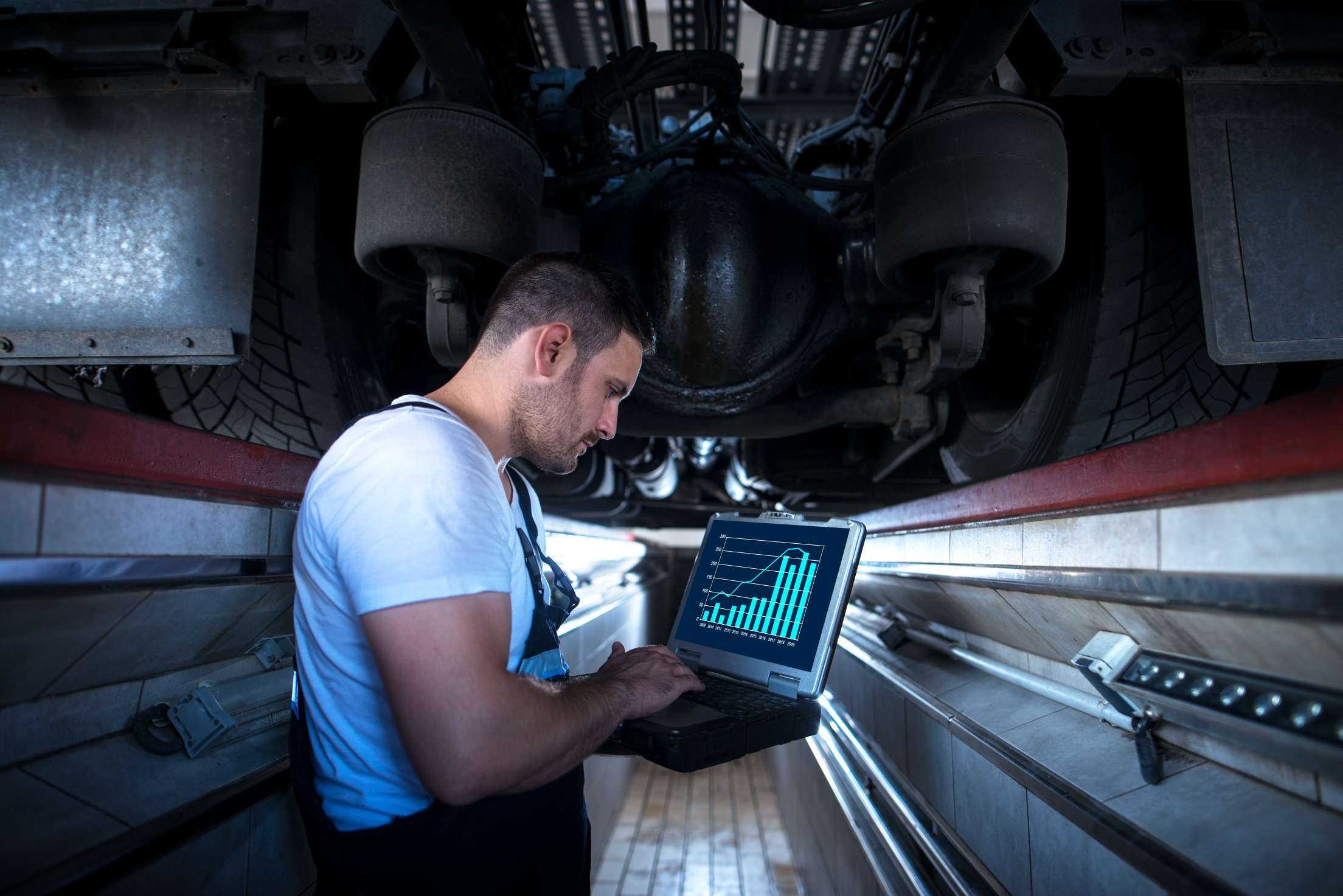 Professional vehicle mechanic using diagnostic equipment in truck workshop